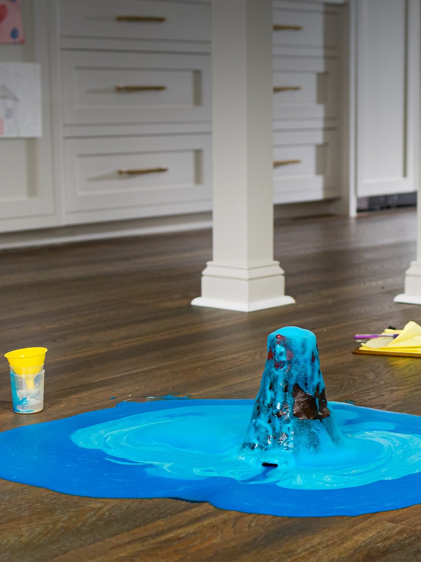 Siblings conducting a science volcano experiment on hardsurface floors